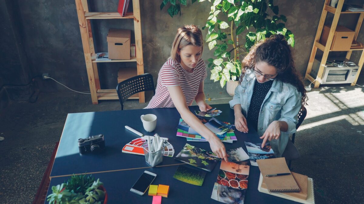 Two women look at photos at a table.